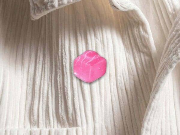 Pink French Fancy pin badge pinned to a white corduroy shirt.