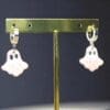 Polymer Clay Ghost earrings on a metal stand against a dark black background.