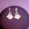 A pair of polymer clay ghost earrings against a dark purple background.