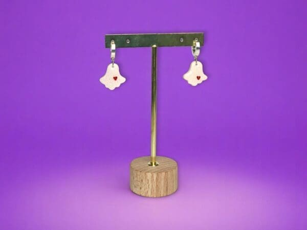Polymer Clay Ghost earrings on a metal stand against a purple background.