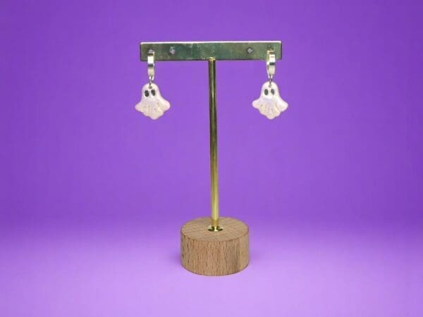 Polymer Clay Ghost earrings on a metal stand against a purple background.